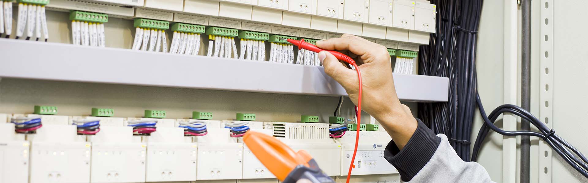 Electrician engineer work tester measuring voltage and current of power electric line in electical cabinet control.